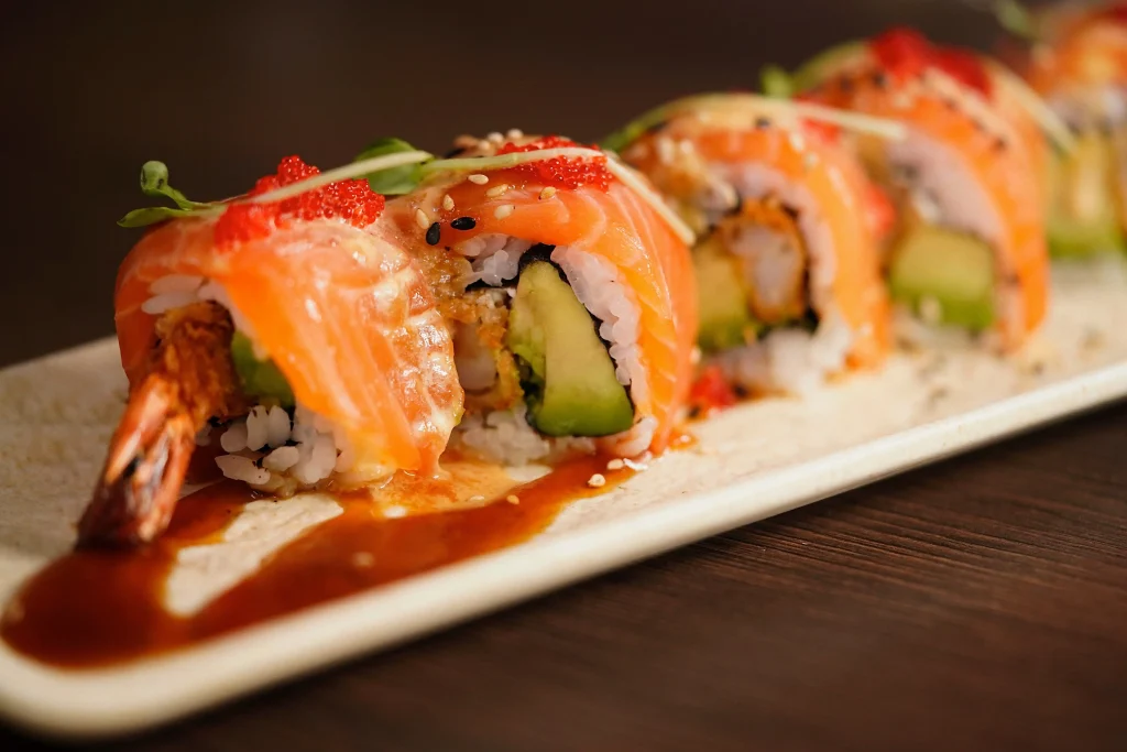 Sushi-Rolle mit Lachs und Avocado auf schwarzem Teller