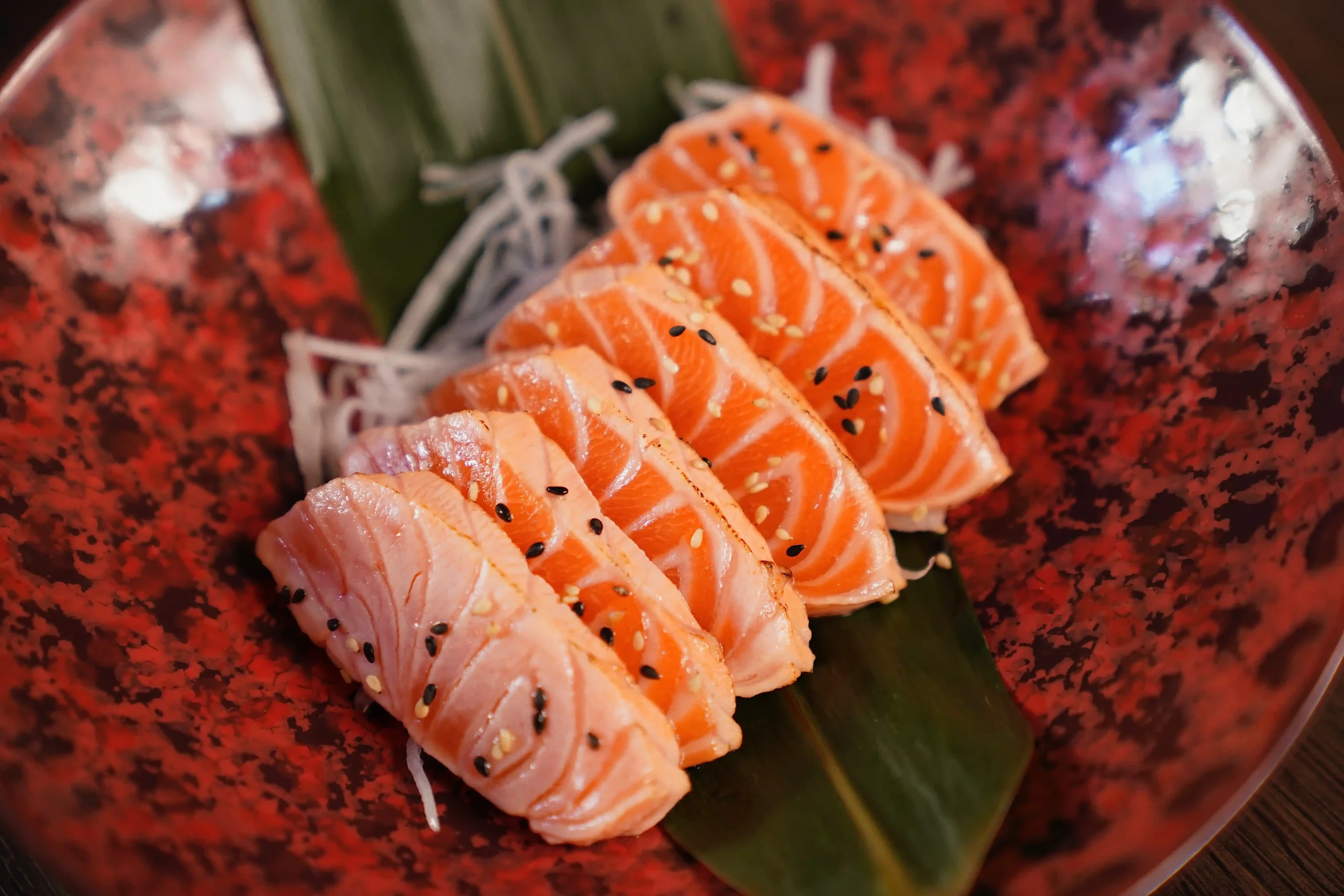 Fein geschnittenes Lachs-Sashimi auf dekorativem Teller